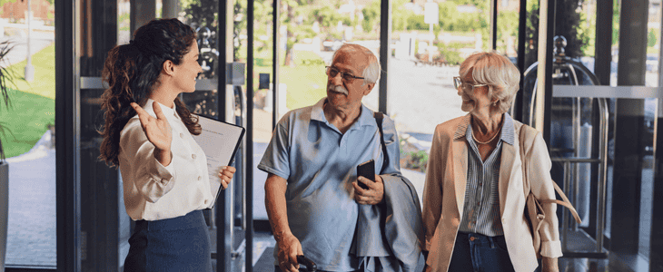A hotel receptionist greets guests at the door
